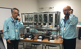 A形交換機(５桁対応)で通話する寺脇さんと千葉さんの写真