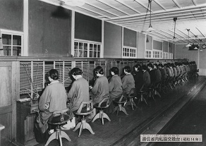 電話交換手たちが手動・共電式構内交換機を操作している当時の写真
