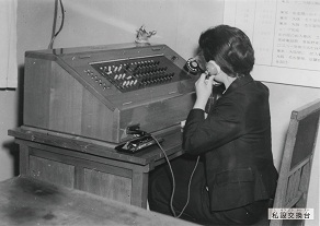 手動・共電式構内交換機(7回線)を操作する電話交換手の様子