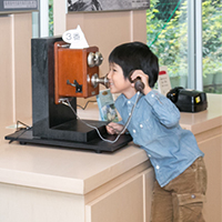 デルビル磁石式電話機をかける男の子の写真
